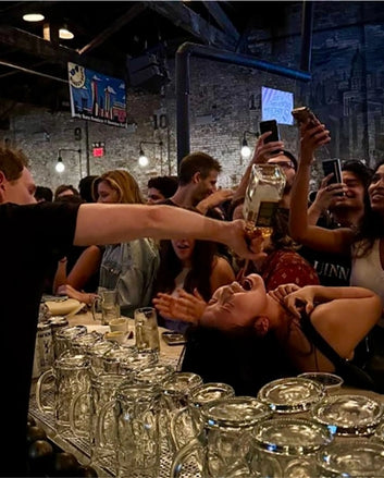 People at a bar with glasses and bottles, celebrating.