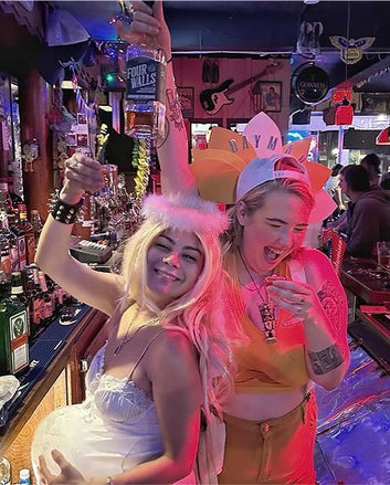 Two people in costumes celebrating with drinks in a bar setting.